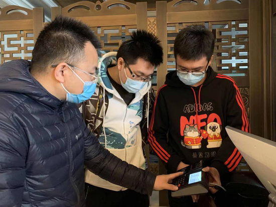 中国联通两会保障人员唐剑波(图左)、朱博(图中)、刘天昊(图右)在代表委员驻地测试大会签到用餐系统。詹益摄