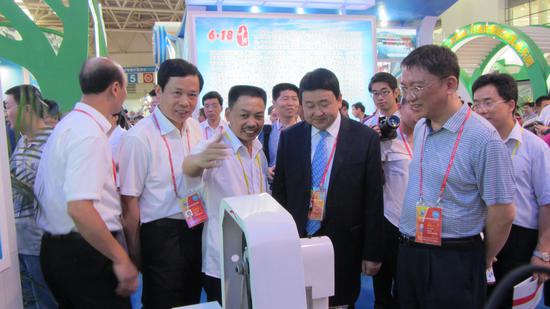 图一 2012年“6·18”时任莆田市委书记的梁建勇参观坚强公司发明的切带机展示 。企业供图。