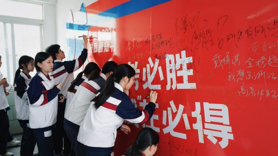 [图注：学生们在“心愿墙”上写下高考愿望]