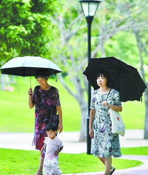 天气忽晴忽雨，市民撑伞在公园内散步。