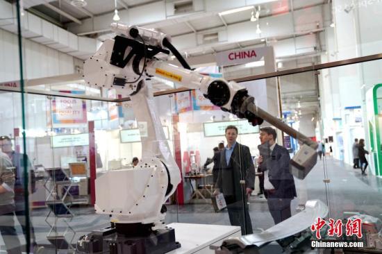 图为两名参观者在德国蔡司公司使用5G通讯的汽车车身自动化检测机器人前驻足。中新社记者 彭大伟 摄