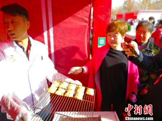 新疆烤包子在美食节上少不了，昌吉市佃坝村味攒劲餐饮烤包子15分钟一锅，出锅就被食客抢购。　王小军 摄