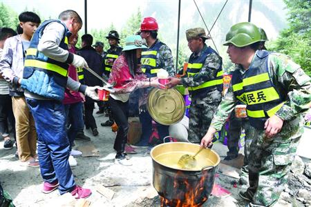 8月9日，在四川省九寨沟县九寨天堂洲际大饭店停车场，救援人员为滞留游客提供食品。