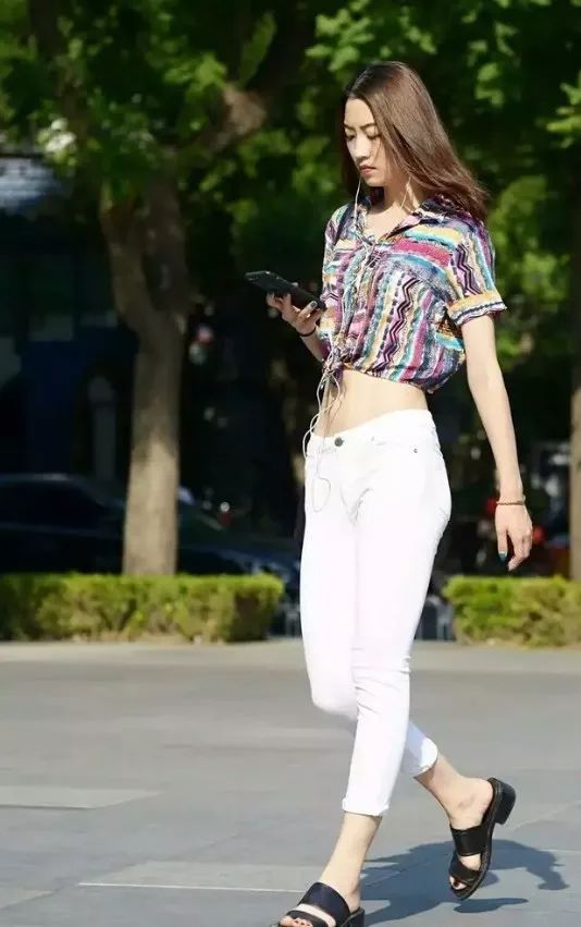 街拍穿白色裤子搭配花衣裳,身姿俏丽动人的性感美女姐姐