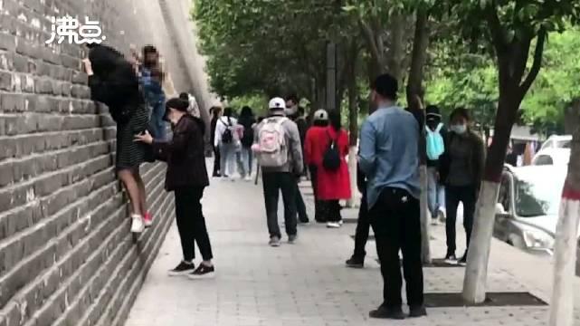 多名游客攀爬西安城墙拍照