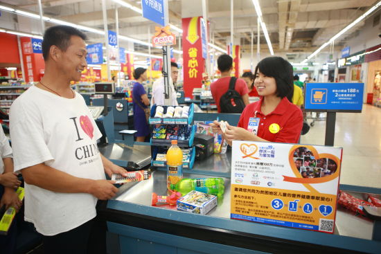 沃尔玛购物广场北京宣武门店收银员正在向顾客介绍你“沃”一起，为爱加餐项目的捐款信息