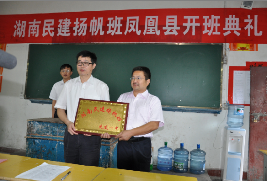 2011年9月8日，民建省委副主委刘长庚(左)将“湖南民建扬帆班”班牌交到凤凰县一中校长孙建明手中。