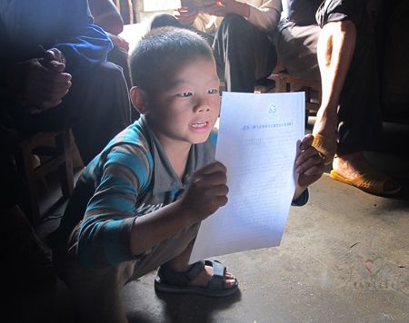 小男孩把《中国扶贫基金会致农户的一封信》念给家人听