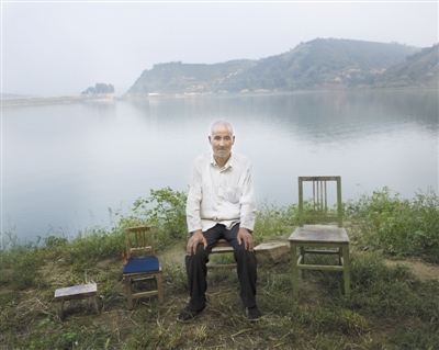  Jiao Zhoucheng, 66, is sitting by the lake near his home in Lingao Town. His three children went out to work.