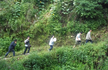 志愿者在村委会干部的陪同下跋山涉水前往受助点