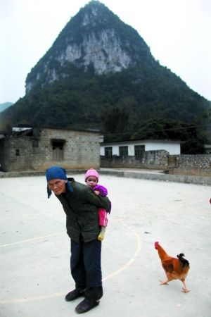 广西天等县天等镇宏魁村龙粟屯，80岁的奶奶背着1岁的小孙子。孩子的父母在广东打工。