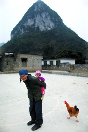 广西天等县天等镇宏魁村龙粟屯,80岁的奶奶背着1岁的小孙子。孩子的父母在广东打工。 广西天等县天等镇宏魁村龙粟屯,80岁的奶奶背着1岁的小孙子。孩子的父母在广东打工。