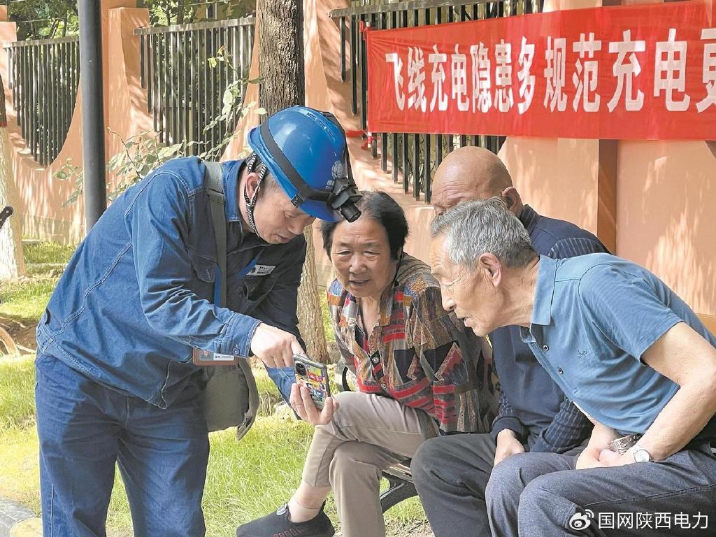 席绪良(左一)向陕西省西安市创汇社区居民介绍供电服务微信群。陈坤 摄