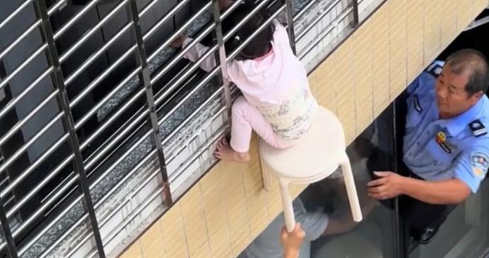 福建漳平一女童“挂”12层防盗网外，头部被卡，邻居和民警用小板凳共同托住