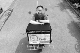 十年前的《变形记》主人公魏程坐在送餐的电动车上。组图/记者金林