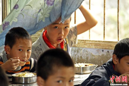 资料图：乡村小学学生食用营养午餐。中新社发 陈畅 摄