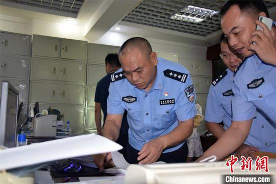 河源警方翻看缴获的虚假账本及材料。 源城警方供图