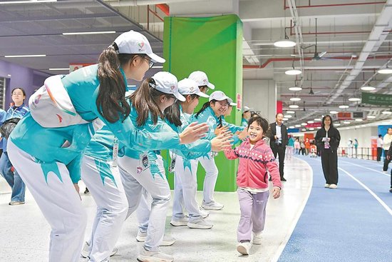 中场志愿者与前来观看开幕式的小朋友击掌 黄焯 摄