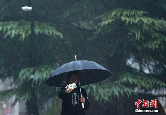资料图:市民在雨中自拍。 中新社记者 刘关关 摄