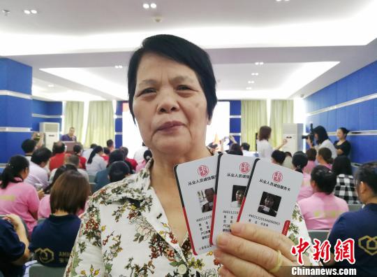 10月11日上午，广州一家家政企业代表展示刚刚领到的“家政服务员诚信服务卡”。　程景伟　摄
