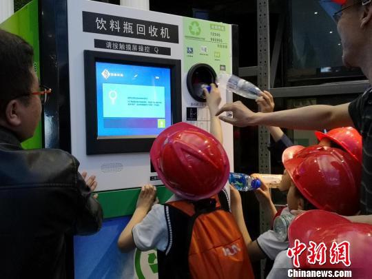 图为学生们拿着手中的瓶子感受饮料瓶智能回收机的便捷。　杜萍 摄