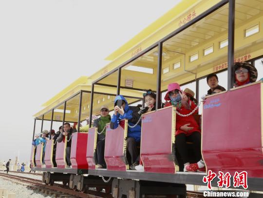 图为茶卡盐湖景区内,游客乘坐小火车进入湖心腹地。 马铭言 摄