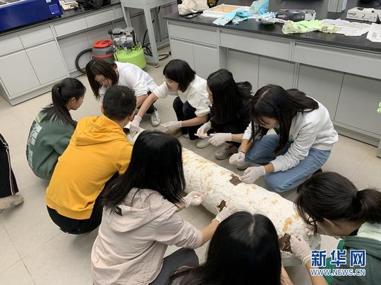 市民们把铁炮周身的纸浆剥掉。新华网发