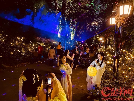 身着汉服的游客在星光点点的萤火虫灯中拍照