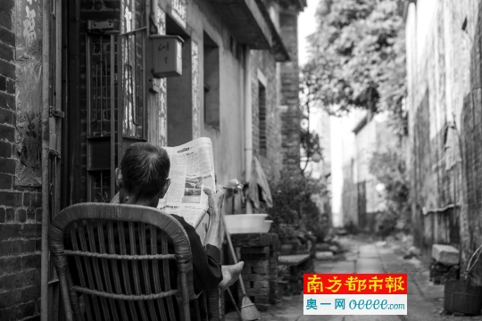 ← 村民在石板小巷里读报。