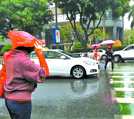 昨日傍晚，天空下起小雨，禅城区人民路侧的行人用塑料袋套住头遮挡雨水。/佛山日报记者周春摄