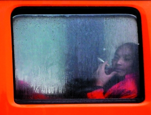 一位市民点着烟，看着车窗外延绵不断的阴雨。