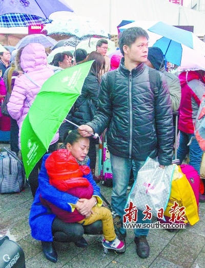 广州火车站广场，一男子为妻子和小孩撑伞。南方日报记者 李细华 摄