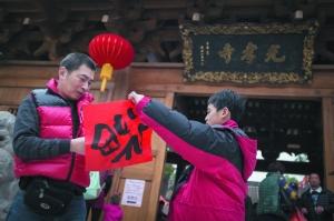 昨日上午，广府庙会祈福系列活动之一的送“福”活动在光孝寺举行，一对父子将刚拿到的“福”字小心叠好。信息时报记者 梁钜聪 实习生 林婕 摄