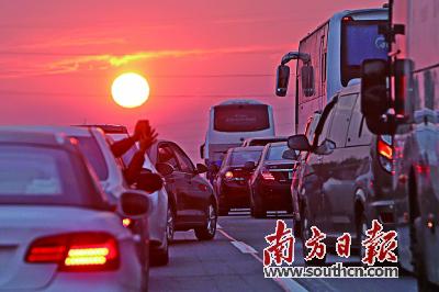 2月1日傍晚，沈海高速公路汕尾路段车流密集，一名乘客用手机拍摄落日。南方日报记者 朱洪波 摄