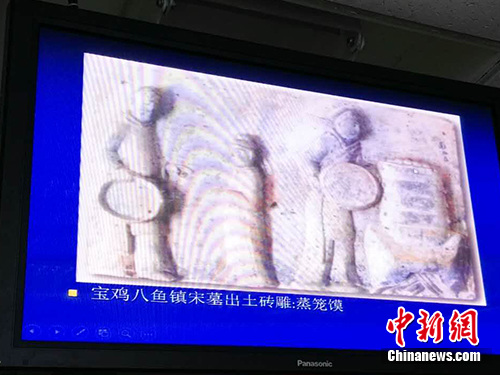 王仁湘在讲座中展示考古照片，图中文物为陕西宝鸡八鱼镇宋墓出土的蒸笼图砖雕。中新网记者 宋宇晟 摄