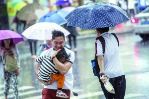 　　昨日，恒宝广场前一名市民抱着小孩急走避雨。