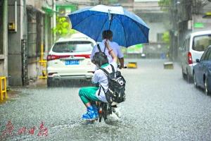 家长冒雨骑车送孩子上学，女孩贴心地把伞往他身上靠。广州日报全媒体记者陈忧子摄