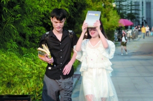 　　昨日广州天气炎热，广州图书馆门口，有年轻人用书挡着脸遮阳匆匆走过。