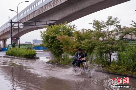 6月12日，杭州街头一位市民骑车飞快越过水坑。当日，浙江多地迎来降雨天气，截至16时，浙江全省近12小时面雨量25.3毫米，多地受降雨影响成“泽国”。中新社记者 沈柯辛 摄