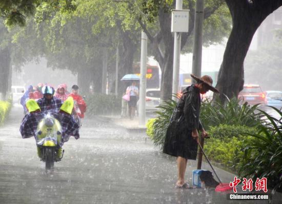 6月16日，广西柳州市遭暴雨侵袭，一名清洁工在雨中扫地。中新社记者 朱柳融 摄