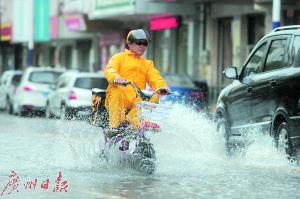 一市民骑车从积水处经过，溅起水花。