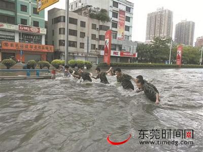 虎门大道上，边检官兵手拉着手趟水前去营救被困群众