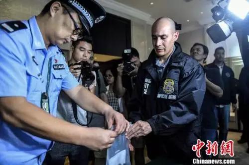 中国警察向美国警察转交扣押的美籍逃犯个人物品。陈骥旻 摄