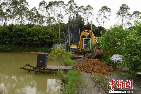 警方用钩机挖开塘堤放水，藏在鱼塘中的嫌疑人“原形毕露”。　程景伟 摄