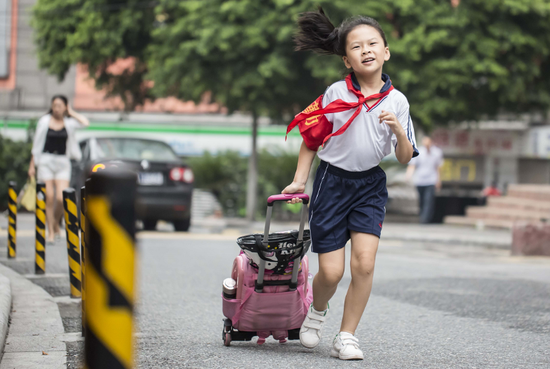 昨日早上7时30分，广州市昌岗东路小学，不少小学生拖拉杆书包上学。广报全媒体记者陈忧子摄