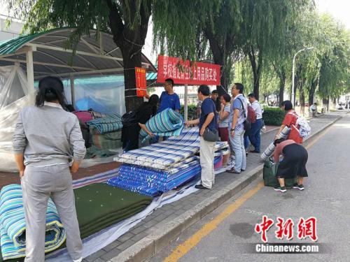 资料图：2017年8月30日，首都师范大学部分院系迎来新生报到。图为学生家长帮孩子购买开学用品。 中新网记者 张尼 摄