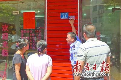 在黄江福海大道上，政府工作人员向商户讲解印有二维码的门楼牌。南方日报记者 孙俊杰 摄