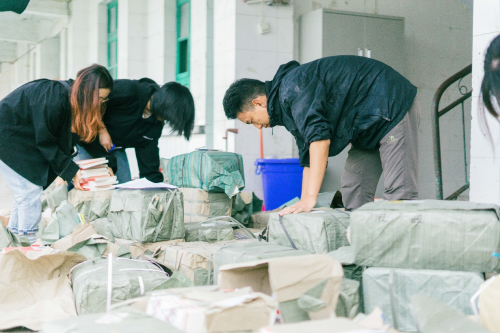 噢啦、志愿者与凉善公益工作人员在分配、打包书籍