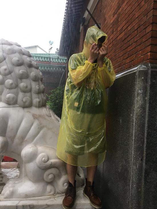 广州日报大洋网记者何晟在雨中等候考生离场