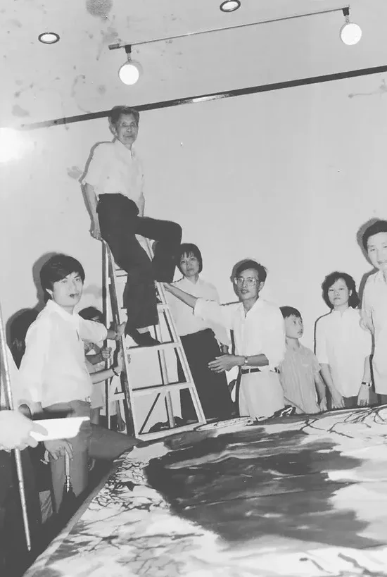 1985年深圳美术节笔会现场,吴冠中爬上梯子观看画作效果。主办方供图